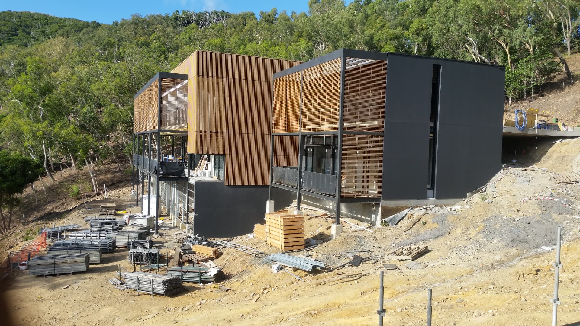 Modern hillside home under construction with timber screening
