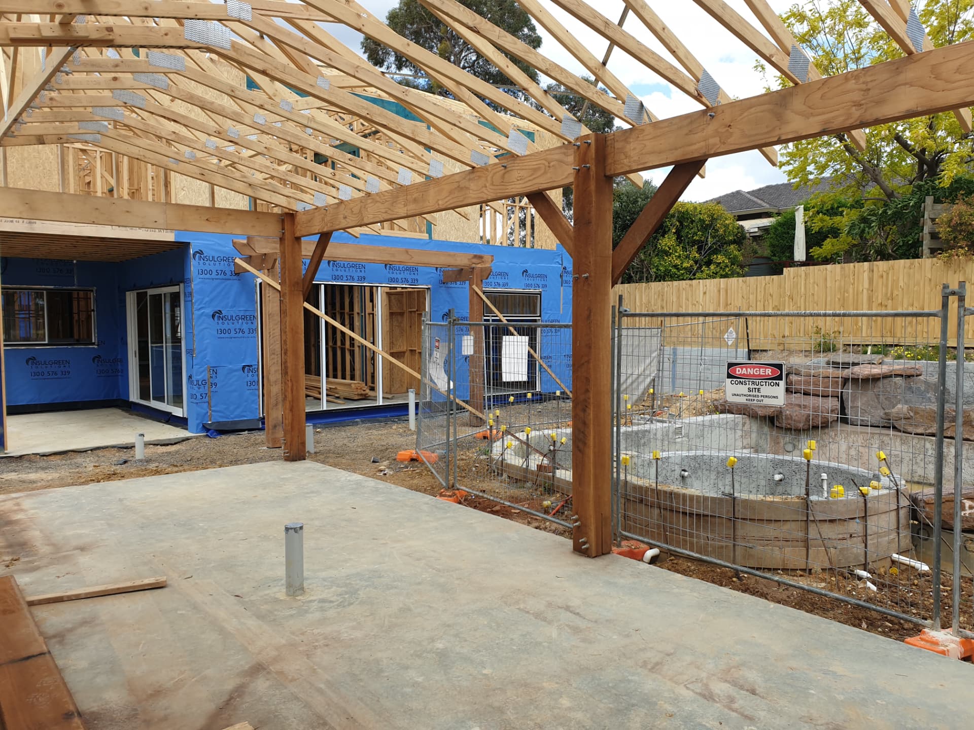 Large hardwood pergola frame beside a house extension